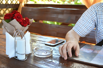 A man looks at the menu in a cafe sits at a wooden table.
