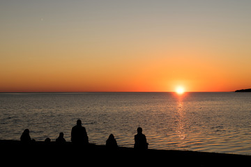 Silhouettes of a family watching an ocean sunset.