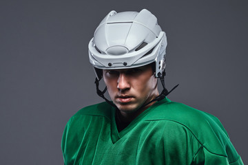 Naklejka premium Close-up portrait of a professional hockey player in a protective sportswear and helmet on a gray background.