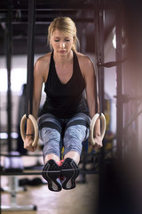 woman working out pull ups with gymnastic rings