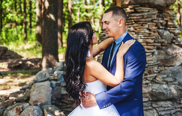 Bride and groom at wedding Day walking Outdoors on spring nature. Bridal couple, Happy Newlywed woman and man embracing in green park. Loving wedding couple outdoor. Bride and groom
