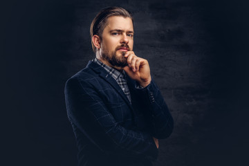 Close-up portrait of a middle-aged man with beard and hairstyle dressed in an elegant blue suit. Isolated on a textured dark background in studio.