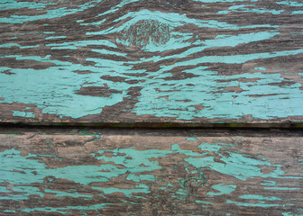 The texture of two wooden planks of old, covered with peeling blue paint.