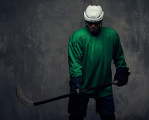 Professional hockey player trains in full equipment with gaming stick against a gray background.