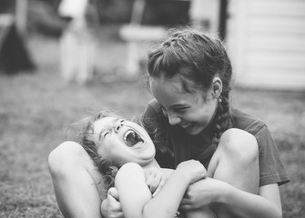 Two Happy little girls laughing and hugging at the  summer park. Black and white photo