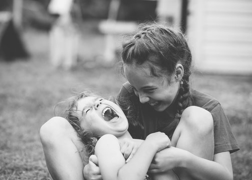 Two Happy Little Girls Laughing And Hugging At The  Summer Park. Black And White Photo