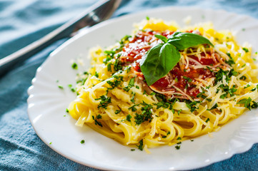 Linguine pasta with fresh tomato sauce, grated cheese and basil in white plate