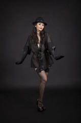 Beautiful young girl dancing in black tunic, black gloves and black hat.