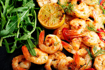 Prawns Shrimps roasted on  pan with lemon and garlic on dark rustic background. top view.