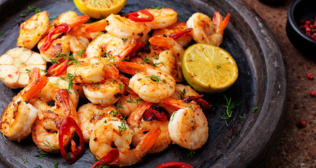 Prawns Shrimps roasted on  pan with lemon and garlic on dark rustic background. top view. - obrazy, fototapety, plakaty