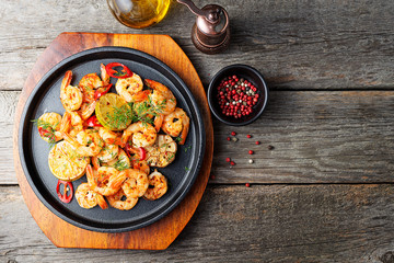 Prawns Shrimps roasted on  pan with lemon and garlic on dark rustic background. top view.