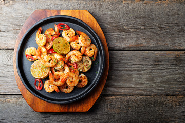 Prawns Shrimps roasted on  pan with lemon and garlic on dark rustic background. top view.