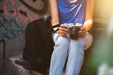 Young woman holding camera in hand sitting on stairs