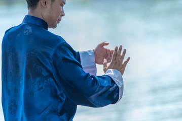 Young man practicing traditional Tai Chi Chuan, Tai Ji and Qi gong in the park for healthy,...