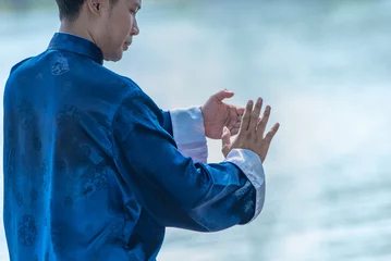  Young man practicing traditional Tai Chi Chuan, Tai Ji and Qi gong in the park for healthy, traditional chinese martial arts concept. © May_Chanikran