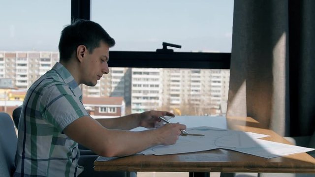Portrait of businessman working on finance graphs in cafe with city view, slow motion. Concept of: cafe table, hand writing, paper work, graphs and charts.