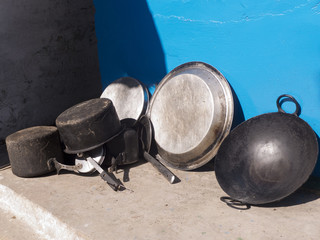 Töpfe und Pfanne vor einer blauen Wand in einer Tempelanlage in der Nähe von Chaukori im Himalaya...