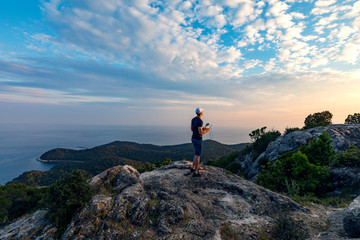 Man operating a drone using a remote controller.Man using drone at sunset for photos and video making 