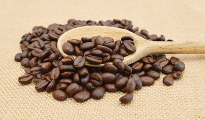 Coffee Beans and wooden spoon in burlap isolated on white.