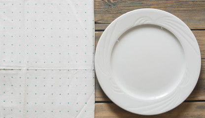 green polka dot towel and empty white plate. Top view with copy space.