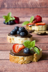 Toast bread with chocolate paste and strawberries blueberries mint on the table Copy space