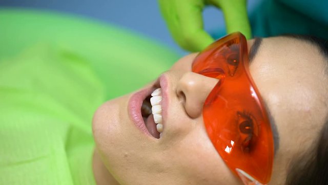 Dental curing light used for teeth treatment, modern equipment, process closeup