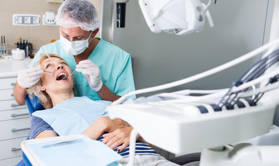 Male dentist treating female patient - obrazy, fototapety, plakaty