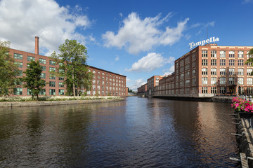 Fototapeta premium Old red brick industrial buildings along the Tammerkoski rapids in downtown Tampere, Finland on a sunny day. Tampella was an industrial company operating there but now it's a district of the same name