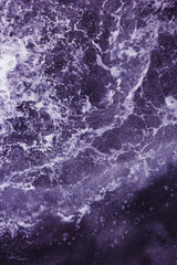 Surface of the sea with waves,  splash,  foam and bubbles at high tide and surf, purple abstract background