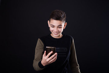 a boy in a black T-shirt is looking at his phone, happiness and joy of winning or news.