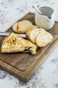 Slice of grilled camembert  with toasted baguettes and cranberry jam