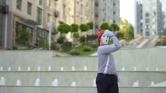 Funny mime fooling around in front of camera and pulling something