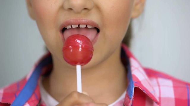 Little girl enjoying lollypop, happy childhood concept, teeth health, closeup