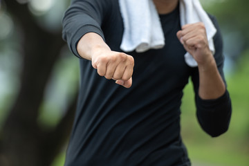 Asian sport man throwing fist or throwing a punch towards in the park.