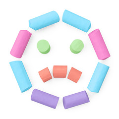 Colored sidewalk or blackboard chalks assembled like sad face emoticon on rough blackboard, 3D rendered