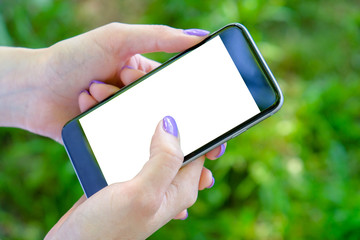 A girl is holding a smartphone outdoor with a grass background. Mockup image.