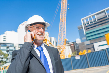 Man architector outdoor at construction area having mobile conversation