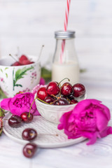 raspberries, cherries and strawberries in bowls, flavors of summer with peony flowers