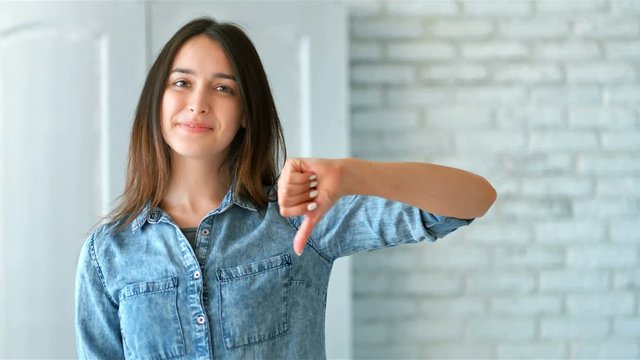 Beautiful young woman showing thumbs down sign to dislike