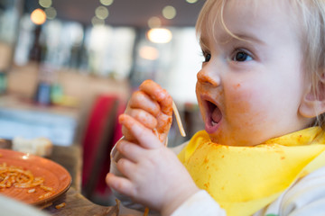 Bebé niña comiendo espaguetti con las manos