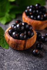 Black currant with leaves in wooden bowls