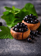 Black currant with leaves in wooden bowls