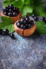 Black currant with leaves in wooden bowls