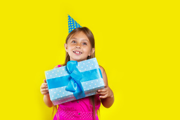 Studio portrait of a little girl wearing a party hat on her birthday. Cute girl open her birthday gift box