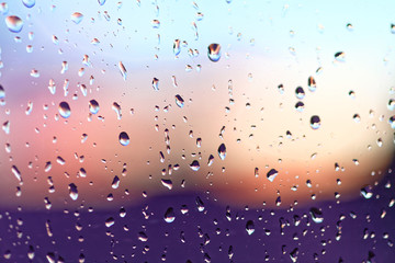 Water rain drops on the window glass on sunset. Shallow depth of field. Cityscape silhouette.