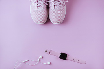 Violet sneakers, headphones and watcheson pink background.