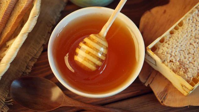 Honey pot and dipper at rustic table with Honey comb, top view