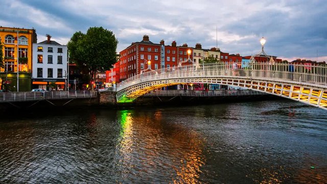 Dublin, Ireland. Night view of famous illuminated Ha Penny Bridge in Dublin, Ireland. Time-lapse at sunset. Light to dark
