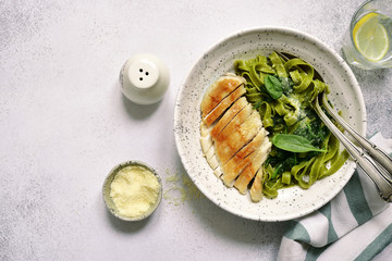 Green spinach pasta tagliatelle with roasted chicken fillet.Top view.