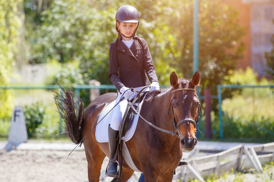 Teenage girl riding bay horse performing dressage test on equestrian competition